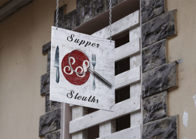 Supper Sleuths Murder Mystery Dinner Games company logo/brand on store sidewalk hanging wood sign.